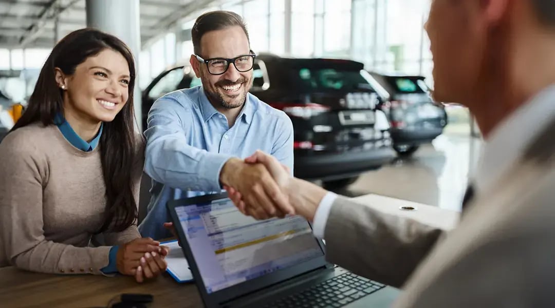 Happy couple making a deal at a car dealership