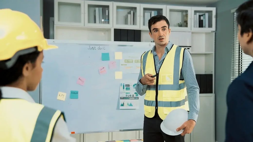 Construction supervisor presenting project metrics to team on whiteboard, highlighting importance of strategic financial planning for contractors.