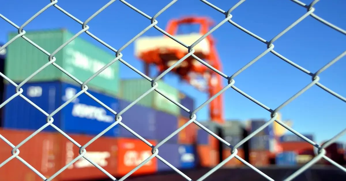 Freight containers stacked behind a wire fence