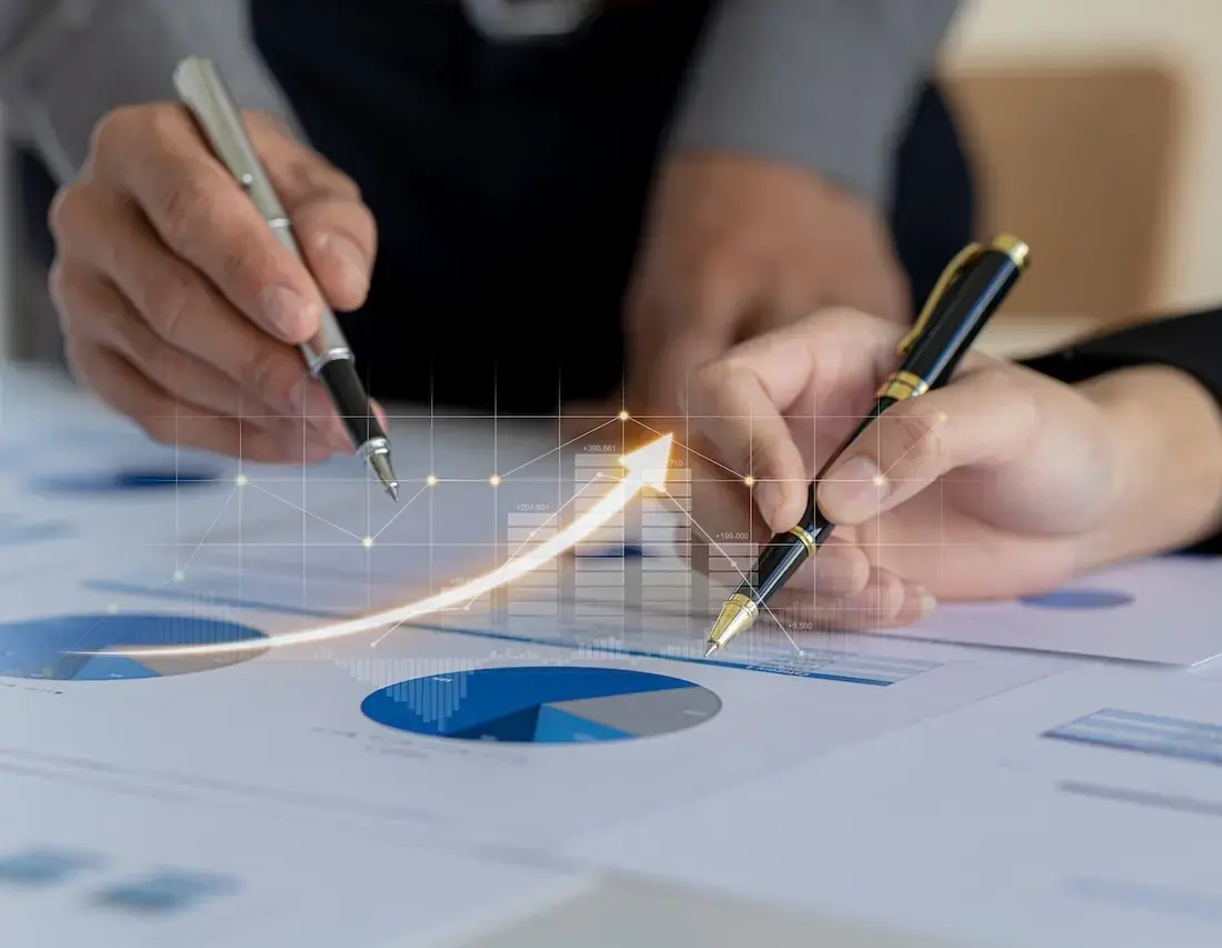 Close-up of two professionals reviewing financial charts and graphs with upward trend arrows